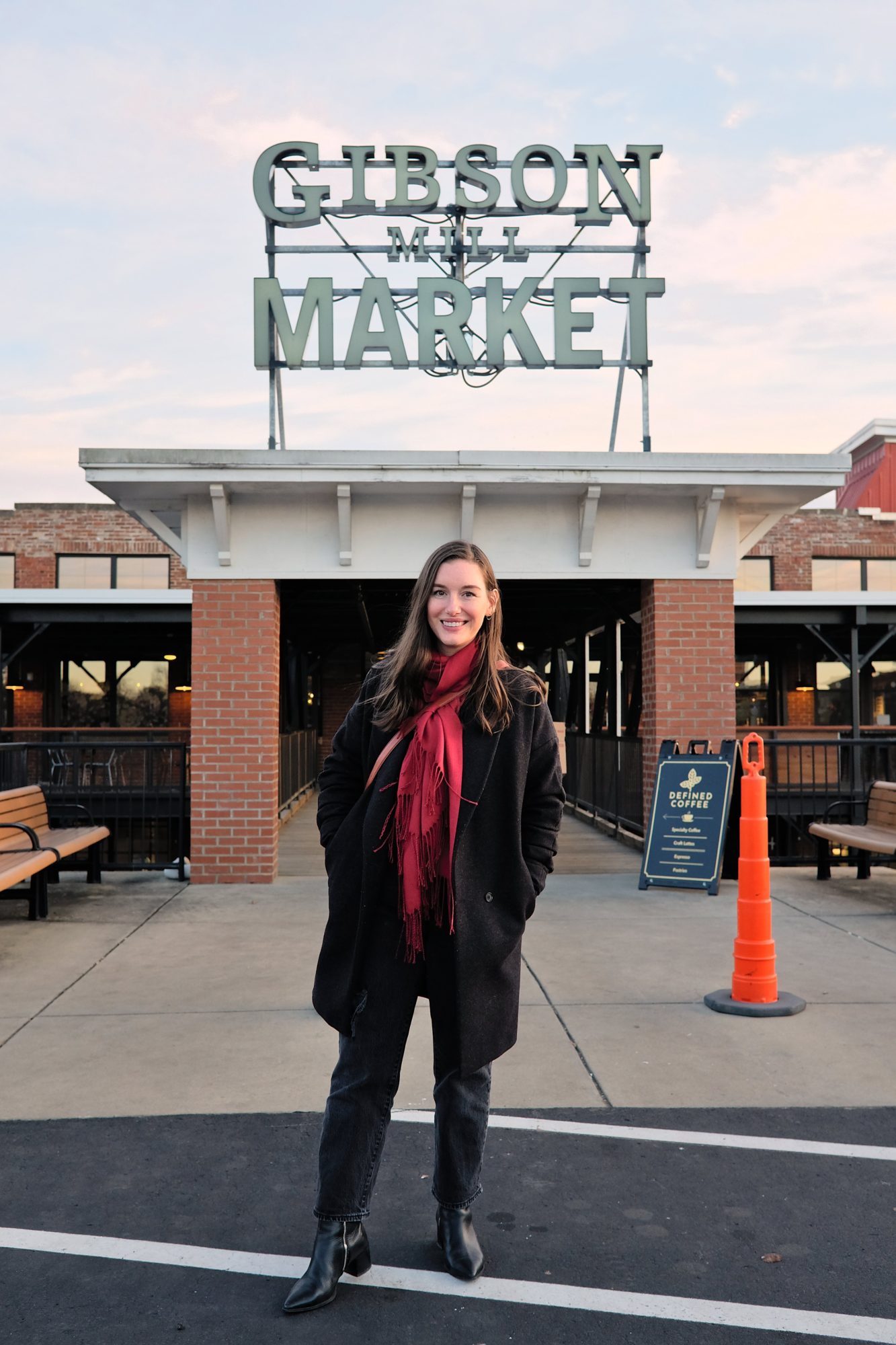 The Ultimate Day Trip Guide for Concord, North Carolina Alyssa wears a black sweater, jeans, and boots with a charcoal coat and red scarf