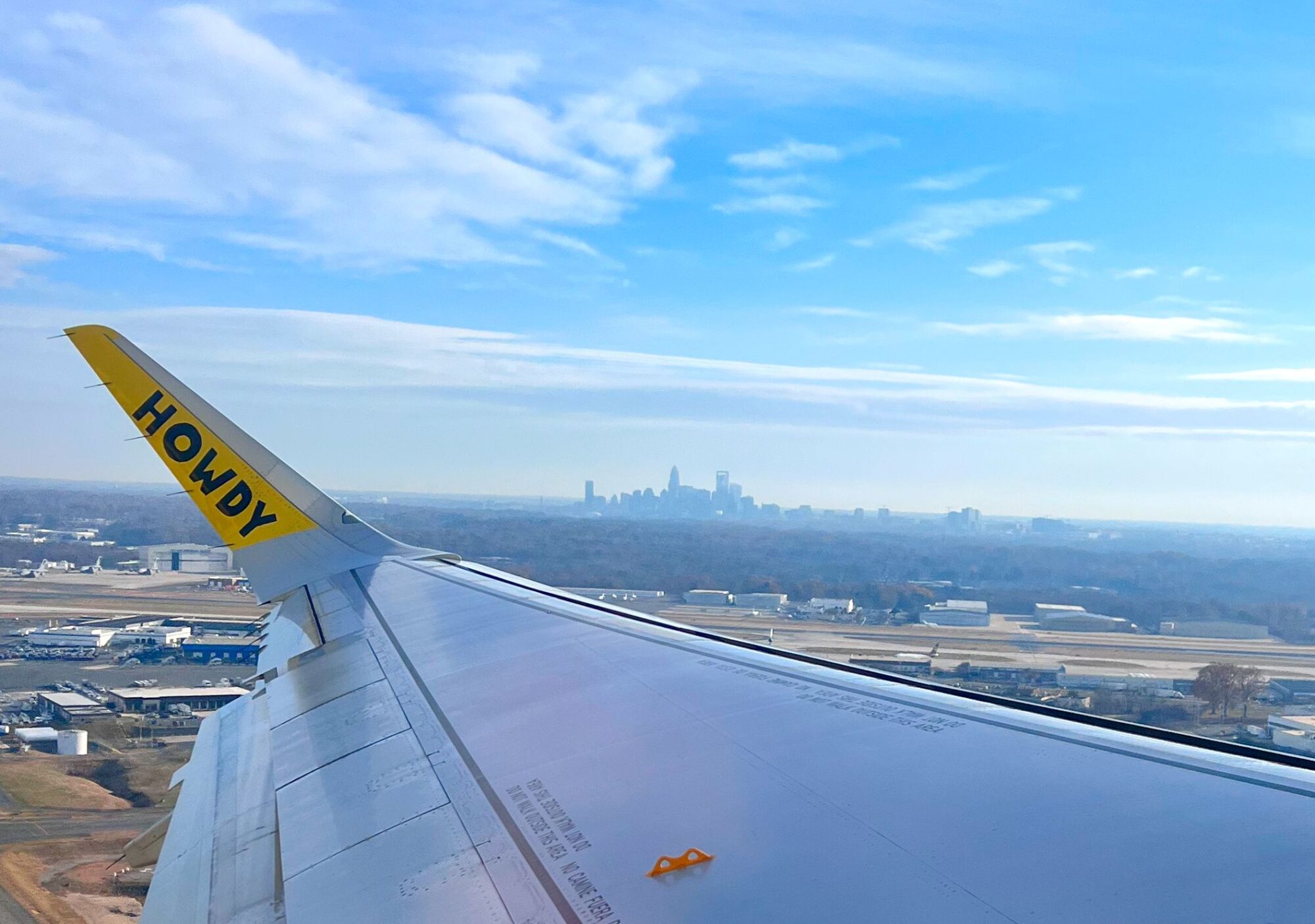 15 Essential Tips for First-Time Flyers with Spirit Airlines A Spirit plane flies over Charlotte with the skyline in the background